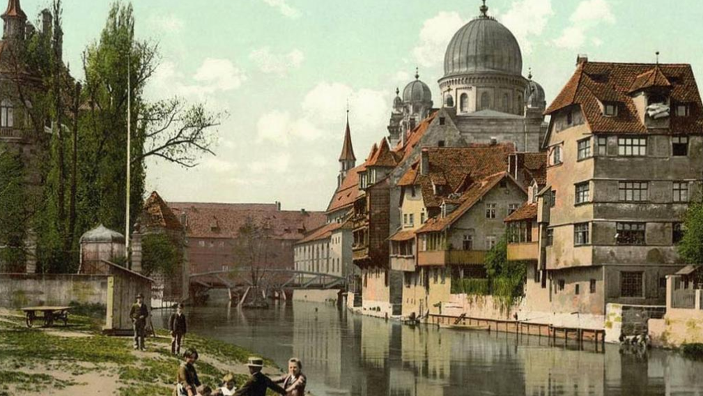 Nürnberg, Insel Schütt in der Pegnitz mit Blick auf die Hauptsynagoge (Postkarte, Farblithographie um 1910).

© Copyright Wikimedia Commons